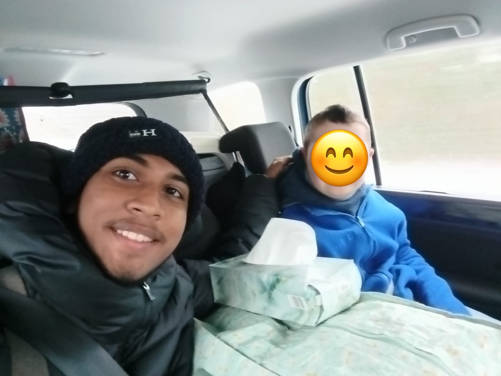 Au-pair und Kind sitzen im Auto auf dem Weg in den Urlaub; das Gesicht des Kindes ist abgedeckt.