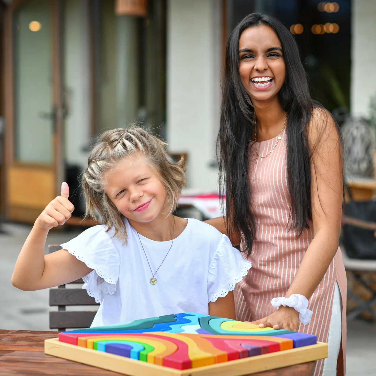 Au-pair und Kind spielen fröhlich mit einem bunten Holzpuzzle