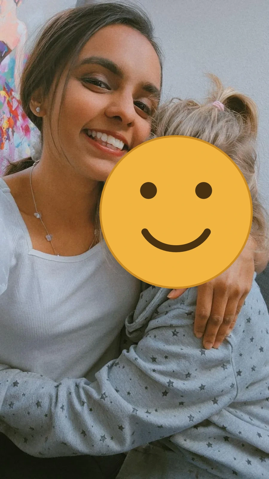 Au-pair umarmt lachend ein Kind im Sterne-Pyjama