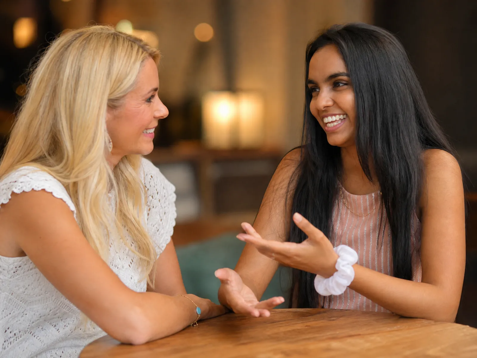 Zwei Frauen sitzen einander am Tisch gegenüber, eine erklärt etwas mit den Händen.