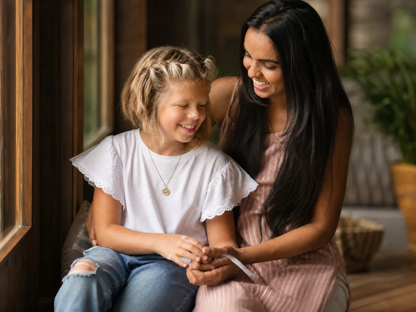 Ein Au-pair sitzt mit einem Kind auf einer sonnigen Veranda